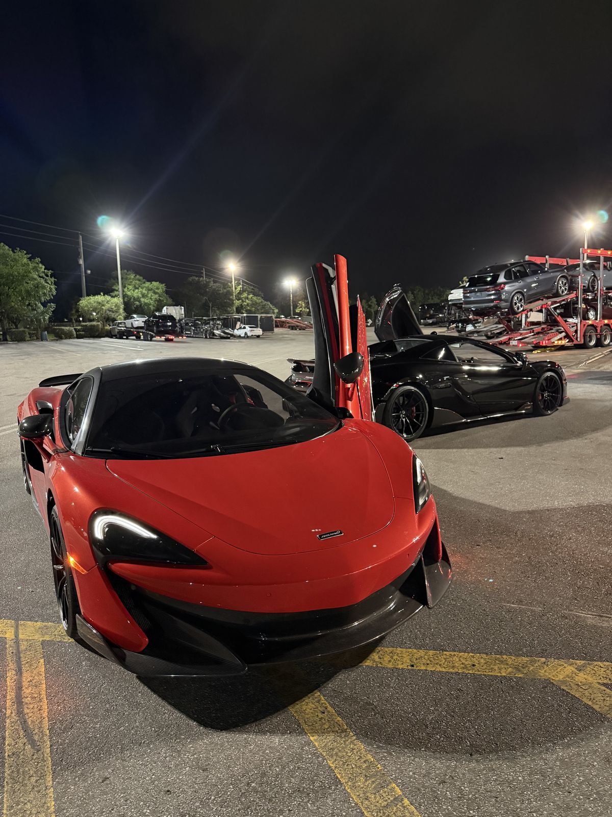 Two McLaren 600LT at night beside car haulers